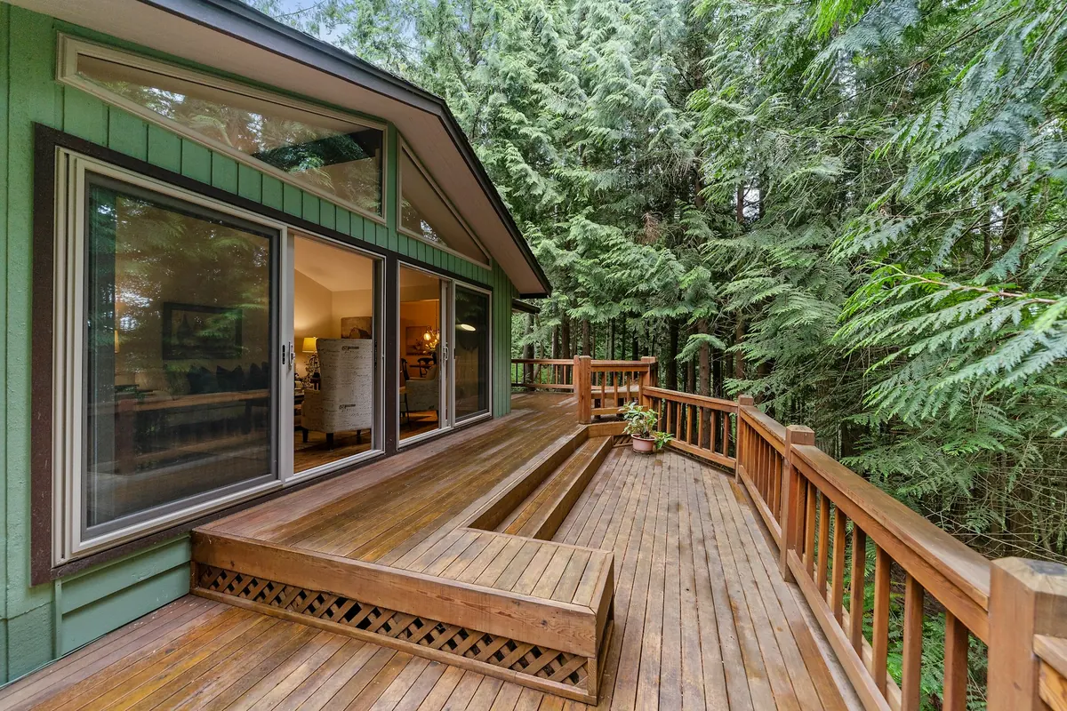 A freshly stained cedar deck with a built-in bench and wooden railing among tall evergreens