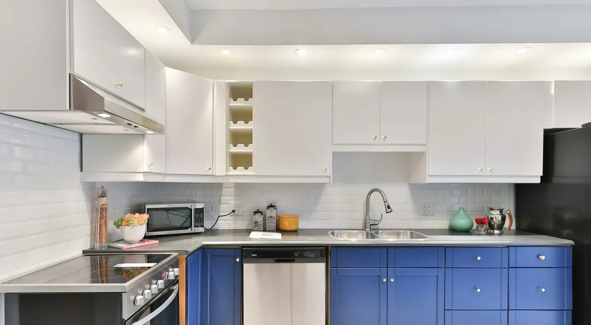A bright kitchen with cobalt blue painted lower cabinets, white uppers and white subway tile