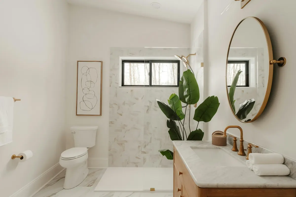 A clean, bright bathroom with a marble-tiled shower, a wooden vanity and rolled white towels