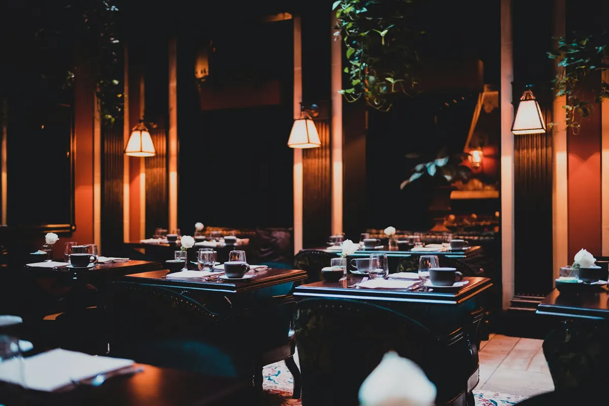 A dim, warm dining room with glowing wall lamps