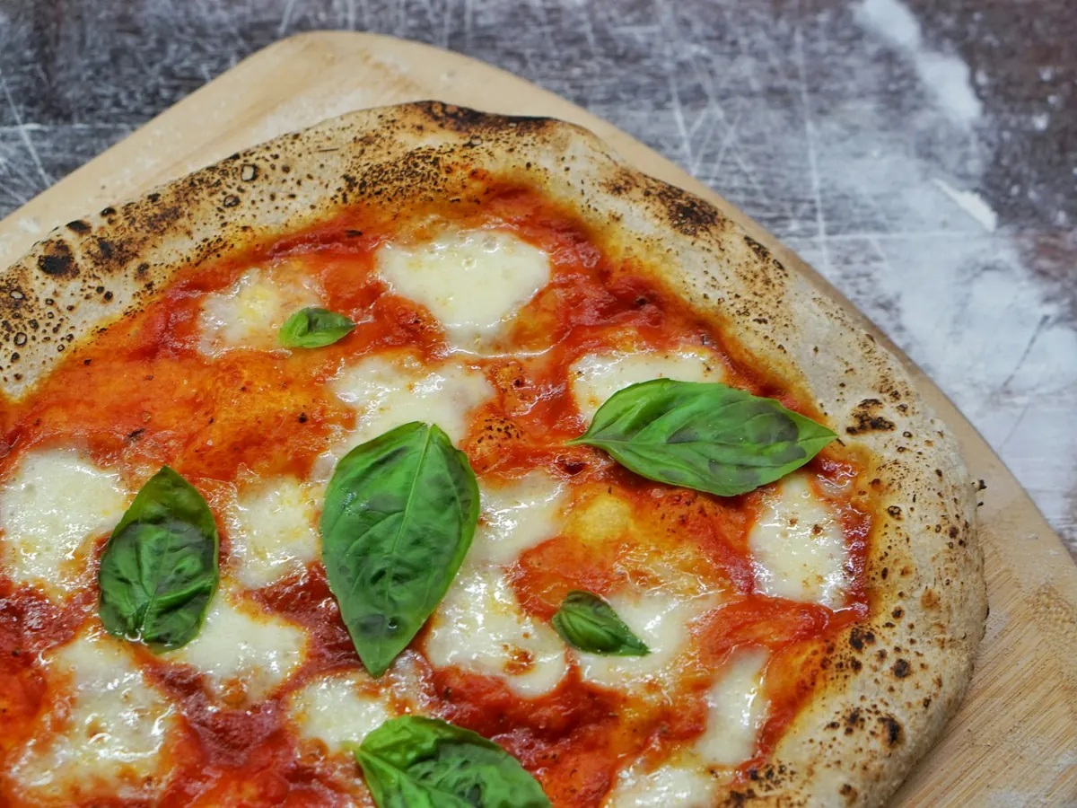 A margherita pizza with a leopard-spotted crust, melted mozzarella and fresh basil