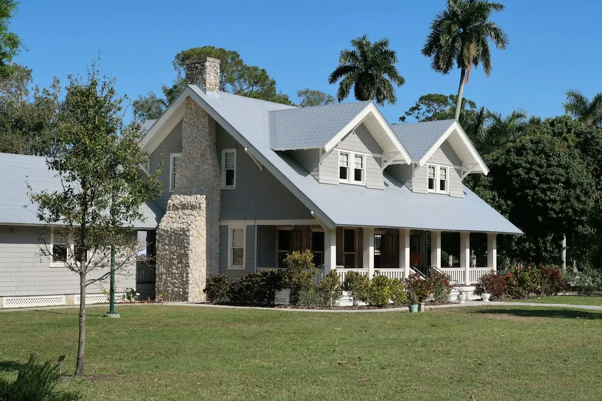 A grey cottage with dormers, a stone chimney and a new light grey roof